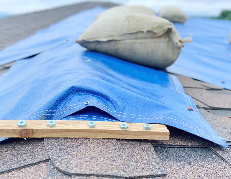 Secured tarp covering exposed roof section